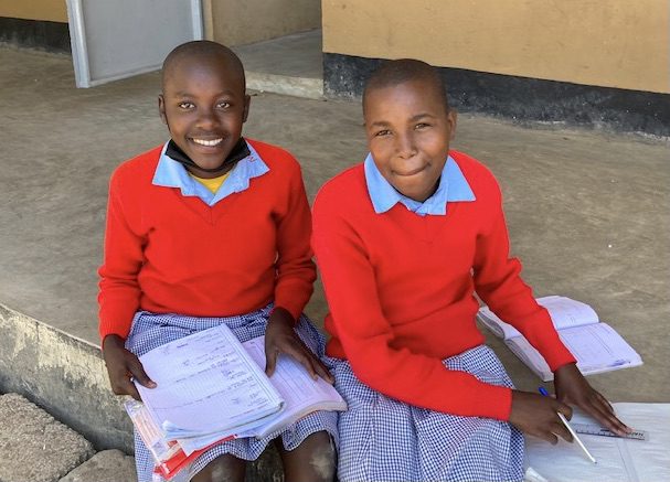 Two Petals of Africa students smiling together with their schoolbooks